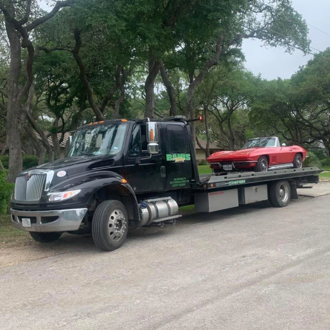 black tow truck hauling corvette