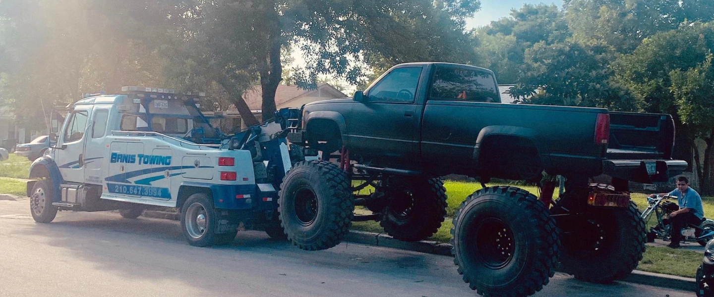 white tow truck hauling mini monster truck